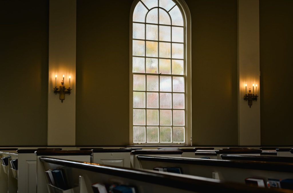 Leere Kirchenbänke mit Licht als Symbol für Stille